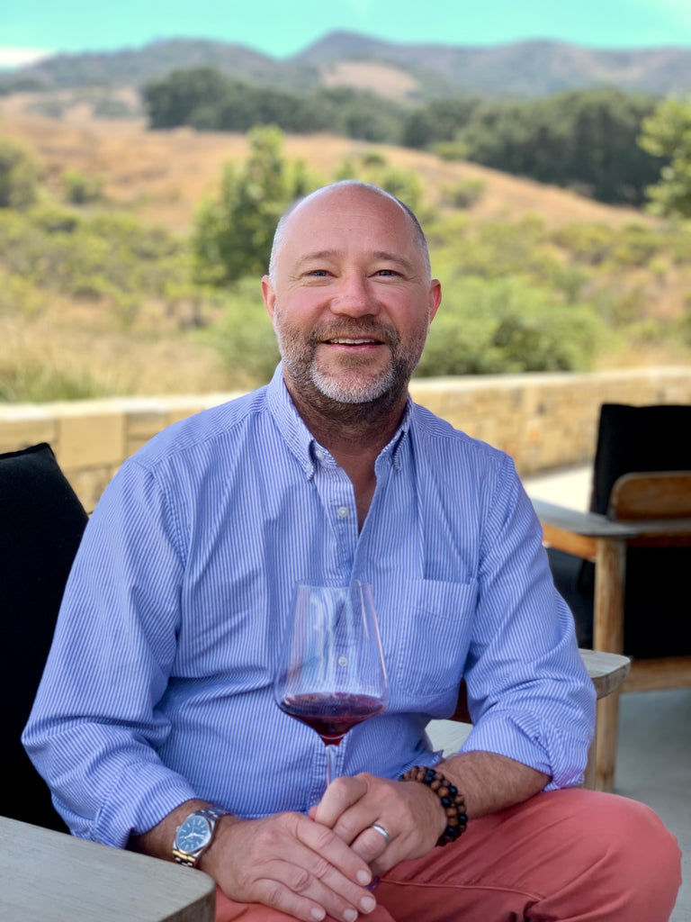 Derek holding a glass of red wine, original Overshare Wines photograph
